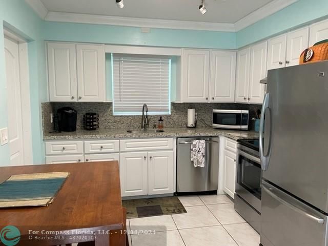 a kitchen with stainless steel appliances granite countertop a refrigerator stove top oven and sink