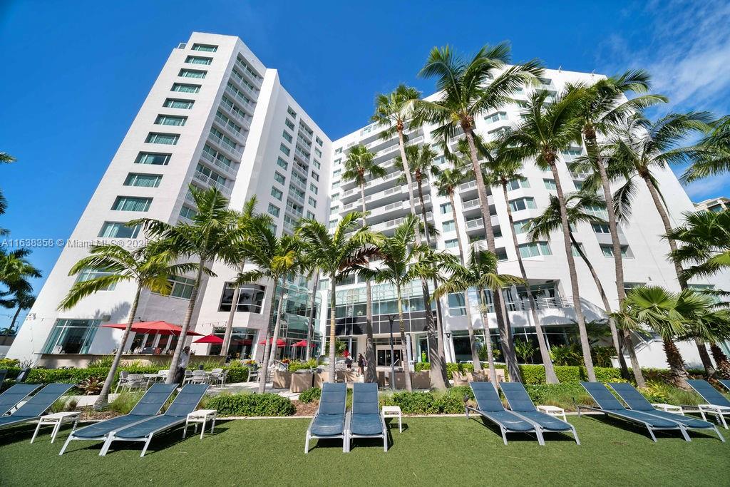 a front view of multi story residential apartment building with yard and outdoor seating