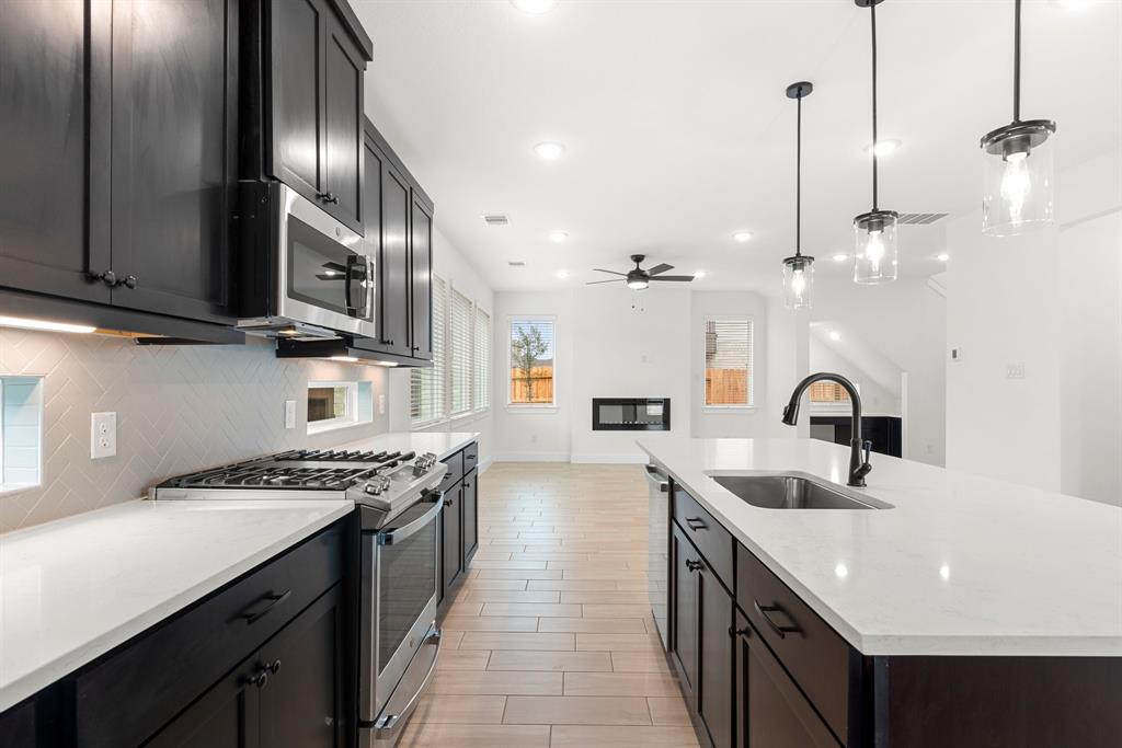 a kitchen with stainless steel appliances granite countertop a sink a stove and a wooden floors