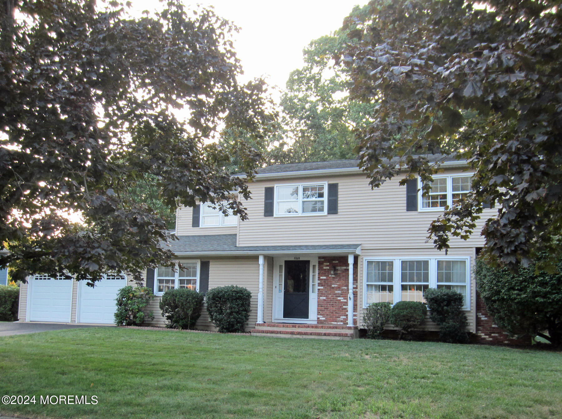 a front view of a house with a garden and trees