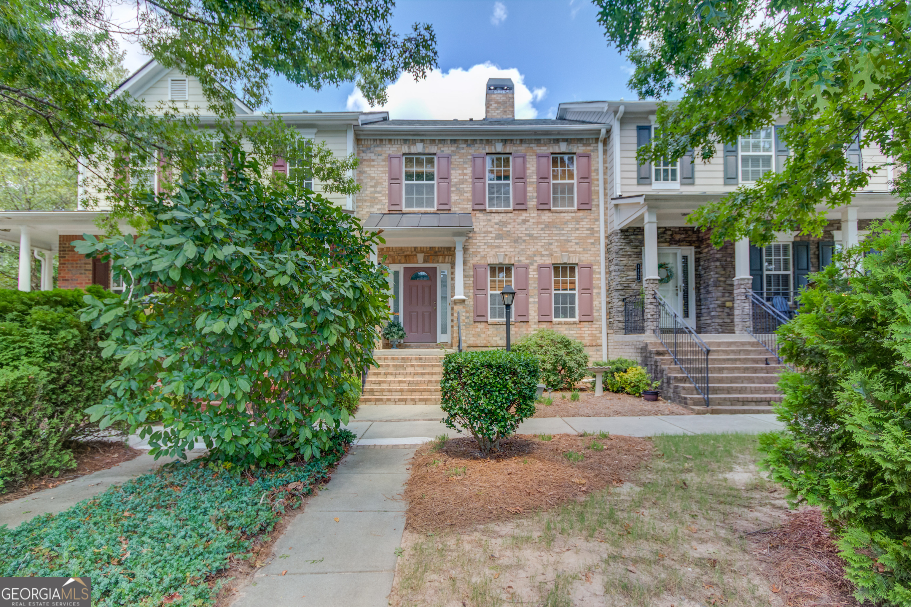 a view of a brick house with large windows and a flower garden