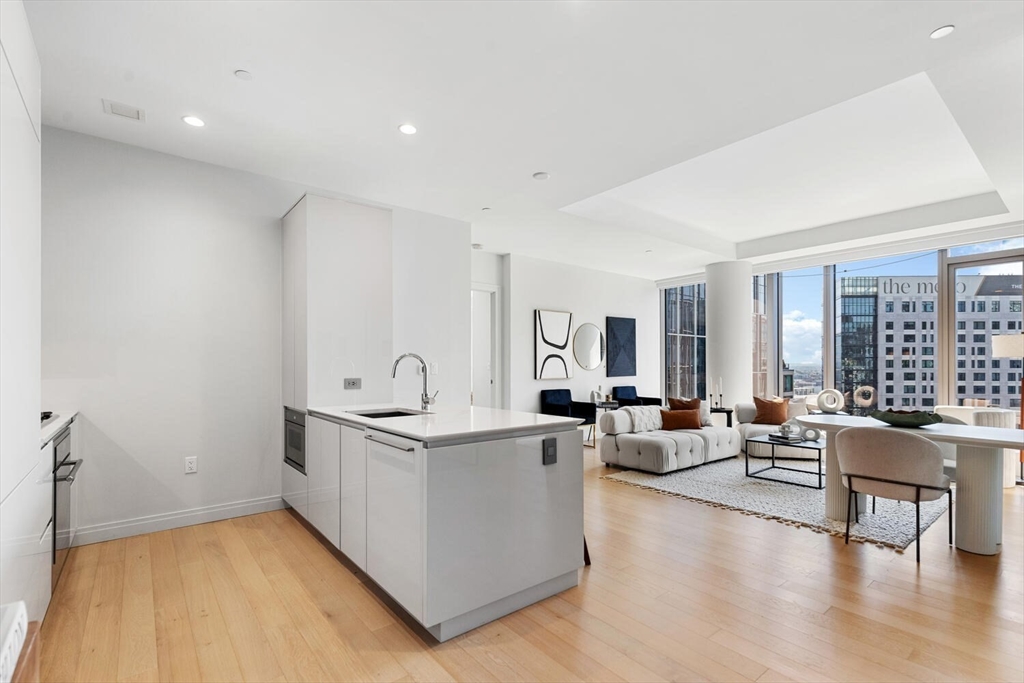 a living room with stainless steel appliances granite countertop furniture and a wooden floor