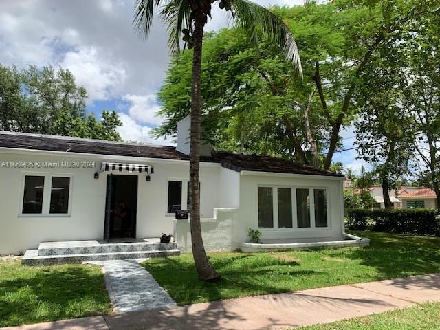 a front view of a house with a garden and trees