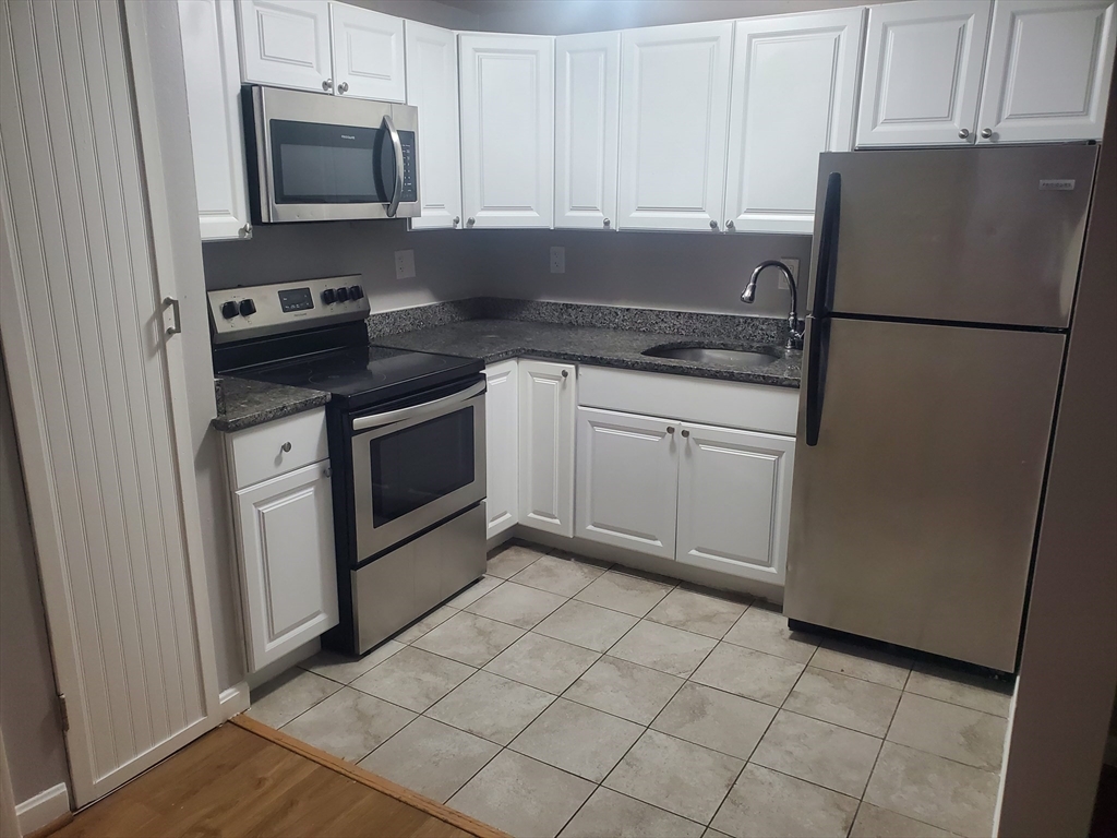 a kitchen with white cabinets and stainless steel appliances