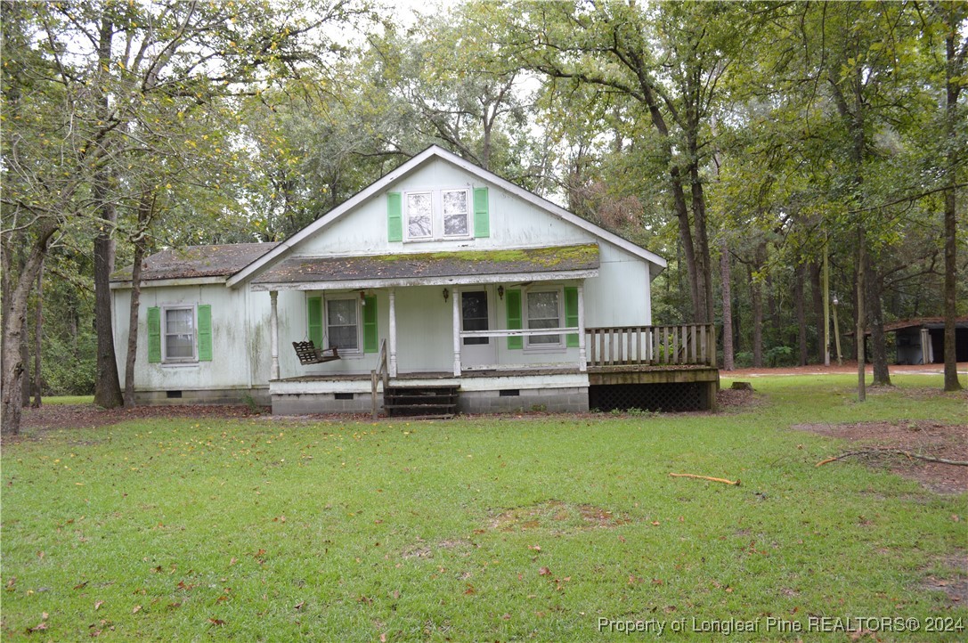 a view of a house with a yard deck and a large tree