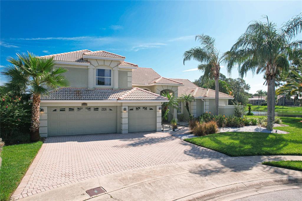 a view of a house with a yard and palm trees