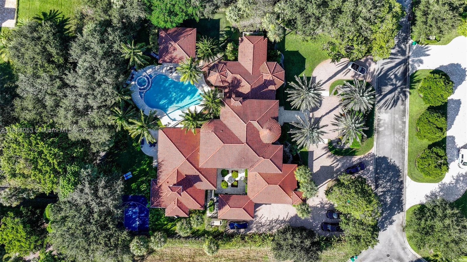 an aerial view of a house with a yard and tennis court