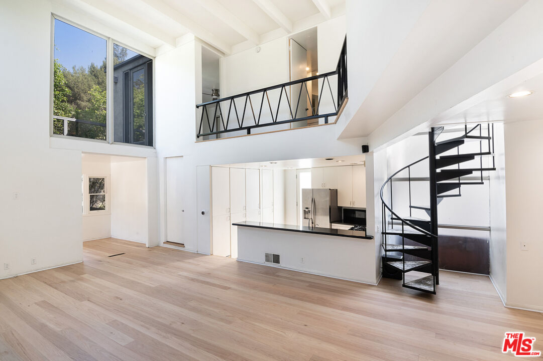 a view of an empty room with stairs and a window