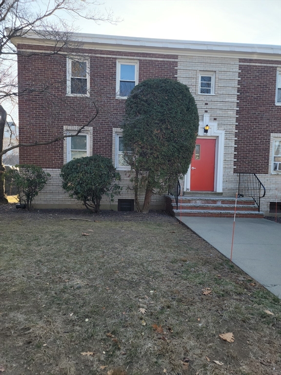 a brick house with a yard and large tree