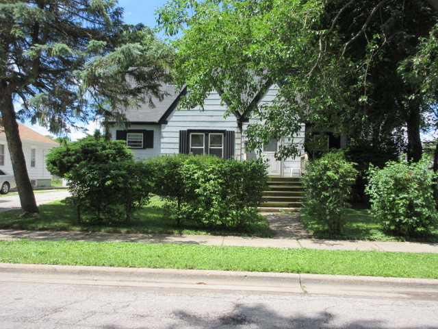 a front view of house with a yard and trees all around