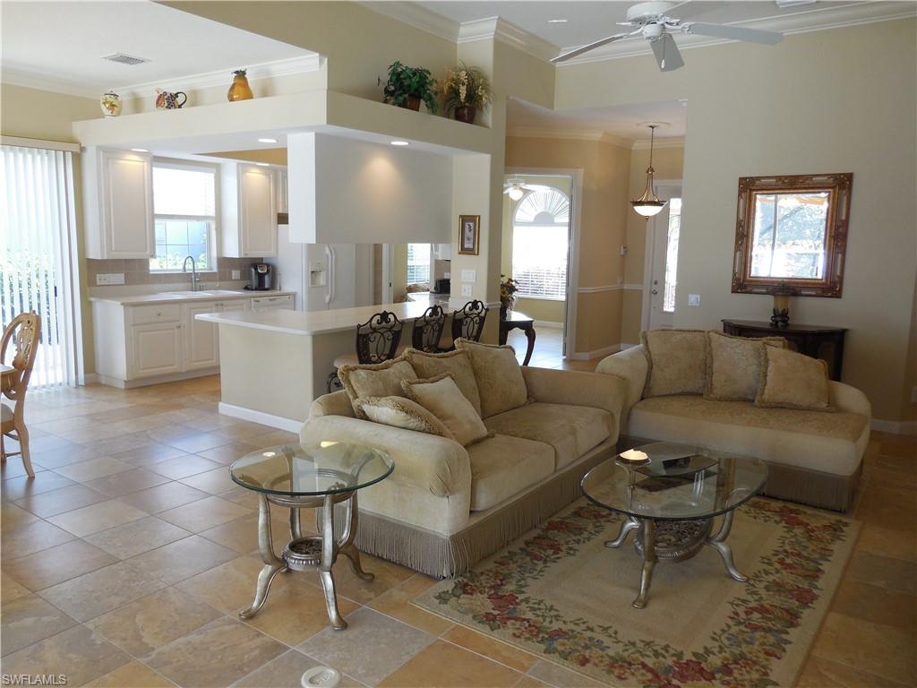 a living room with furniture a wooden floor and a view of kitchen