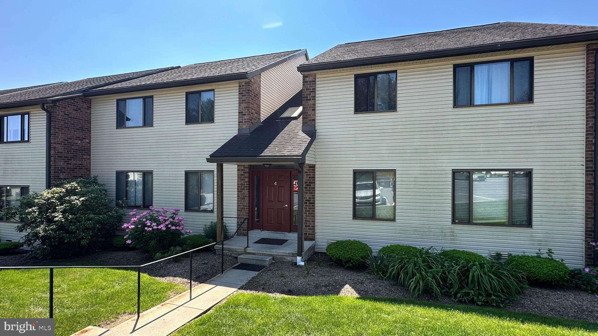 a front view of house and yard with beautiful flowers and green space