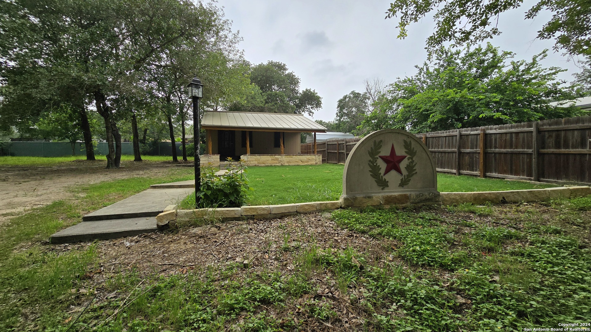 a view of a backyard with large tree and wooden fence