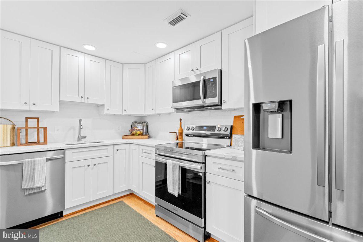 a kitchen with stainless steel appliances granite countertop white cabinets and refrigerator