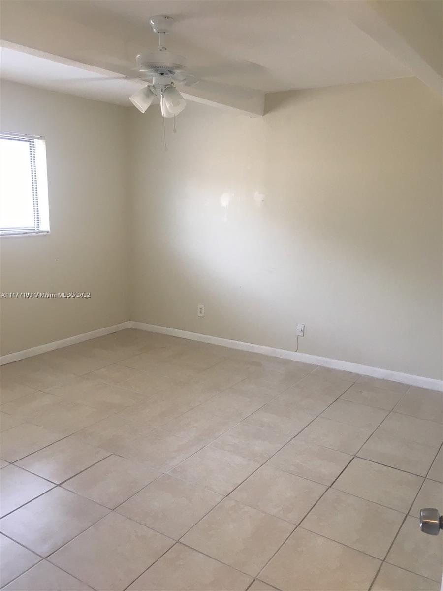 an empty room with a ceiling fan and window