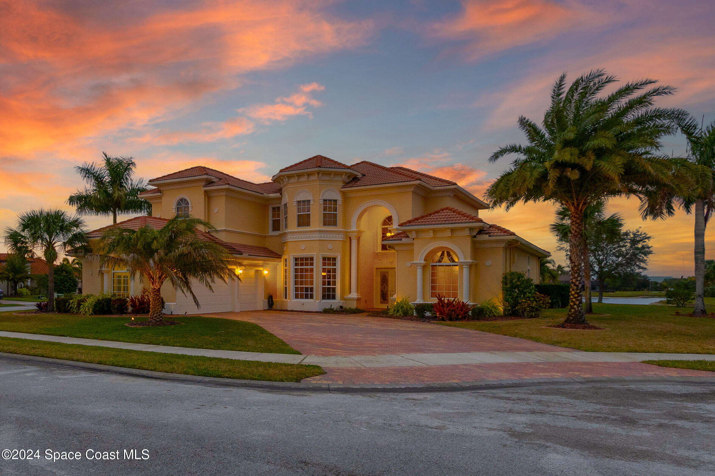 a view of a white house with a big yard and palm trees