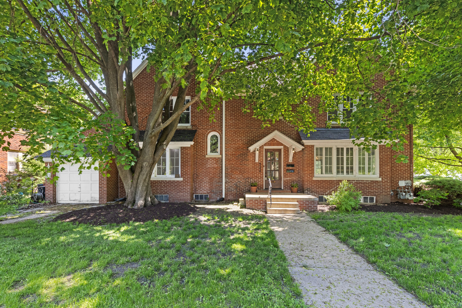 a front view of a house with a yard and trees