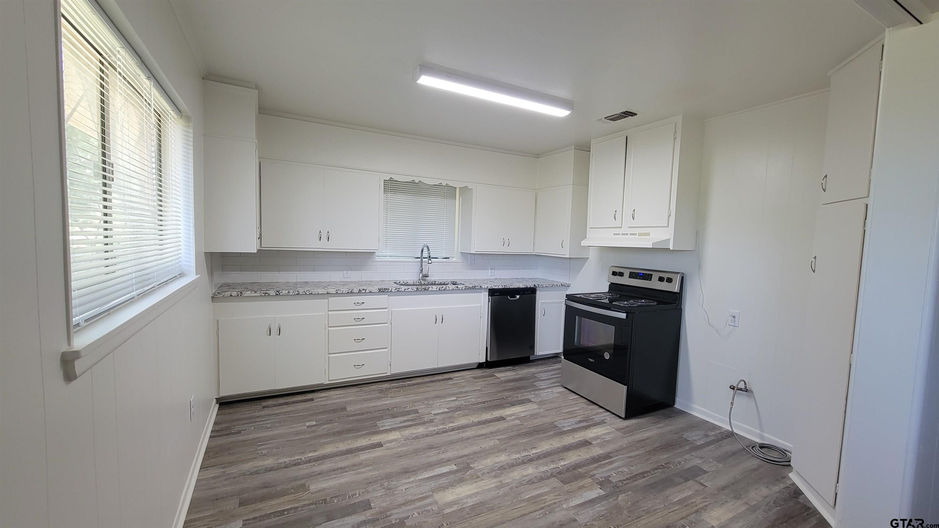 a kitchen with a white cabinets and wooden floor