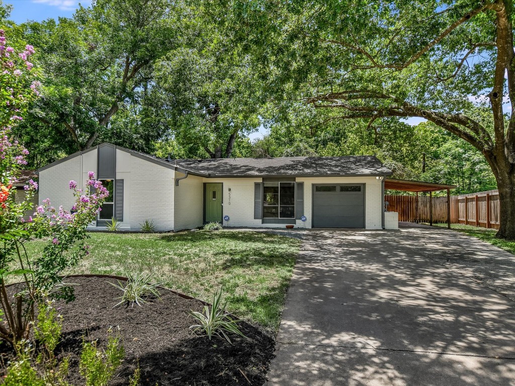 a view of a house with a yard and large trees