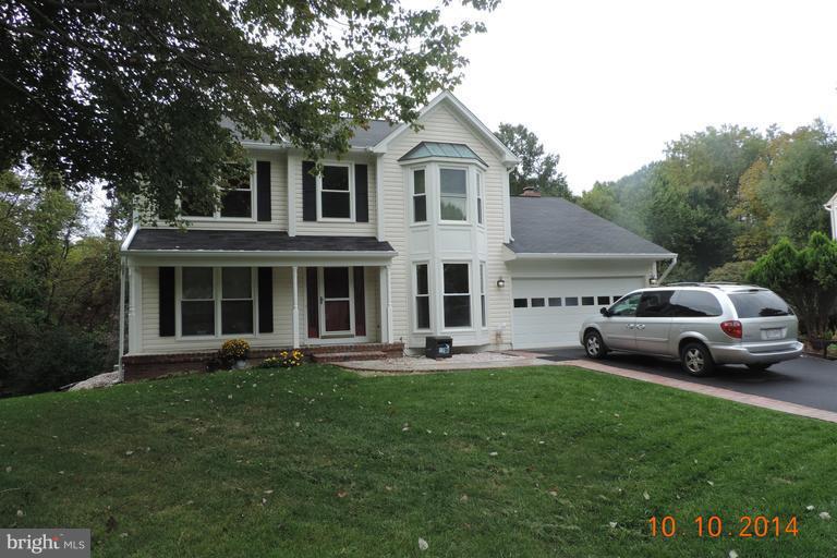 a front view of a house with a garden and trees