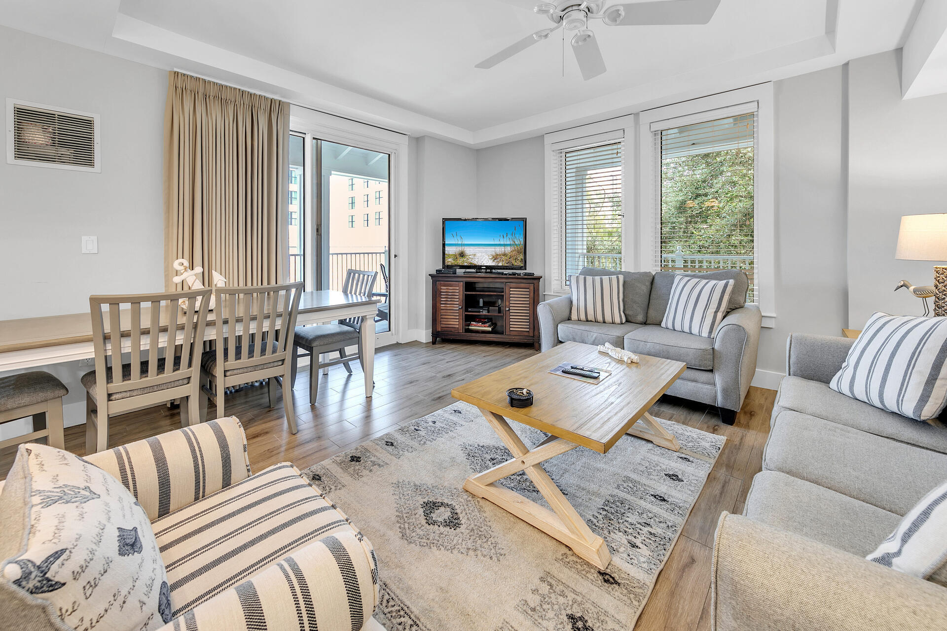 a living room with furniture flat screen tv and large windows