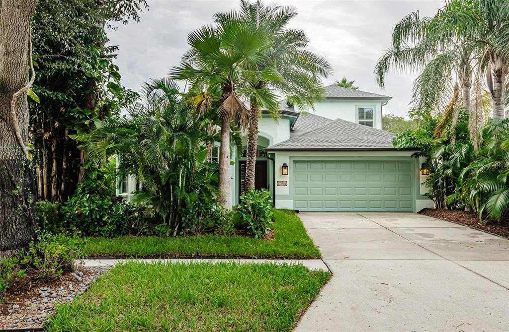 a front view of a house with a garden and palm trees