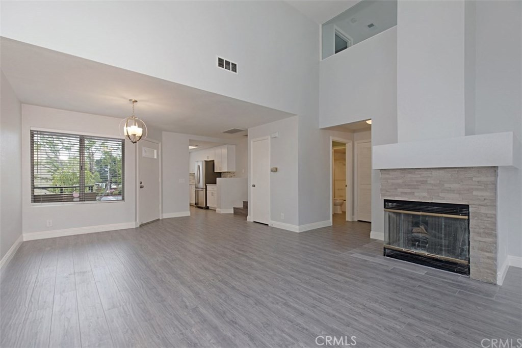 an empty room with wooden floor fireplace and windows