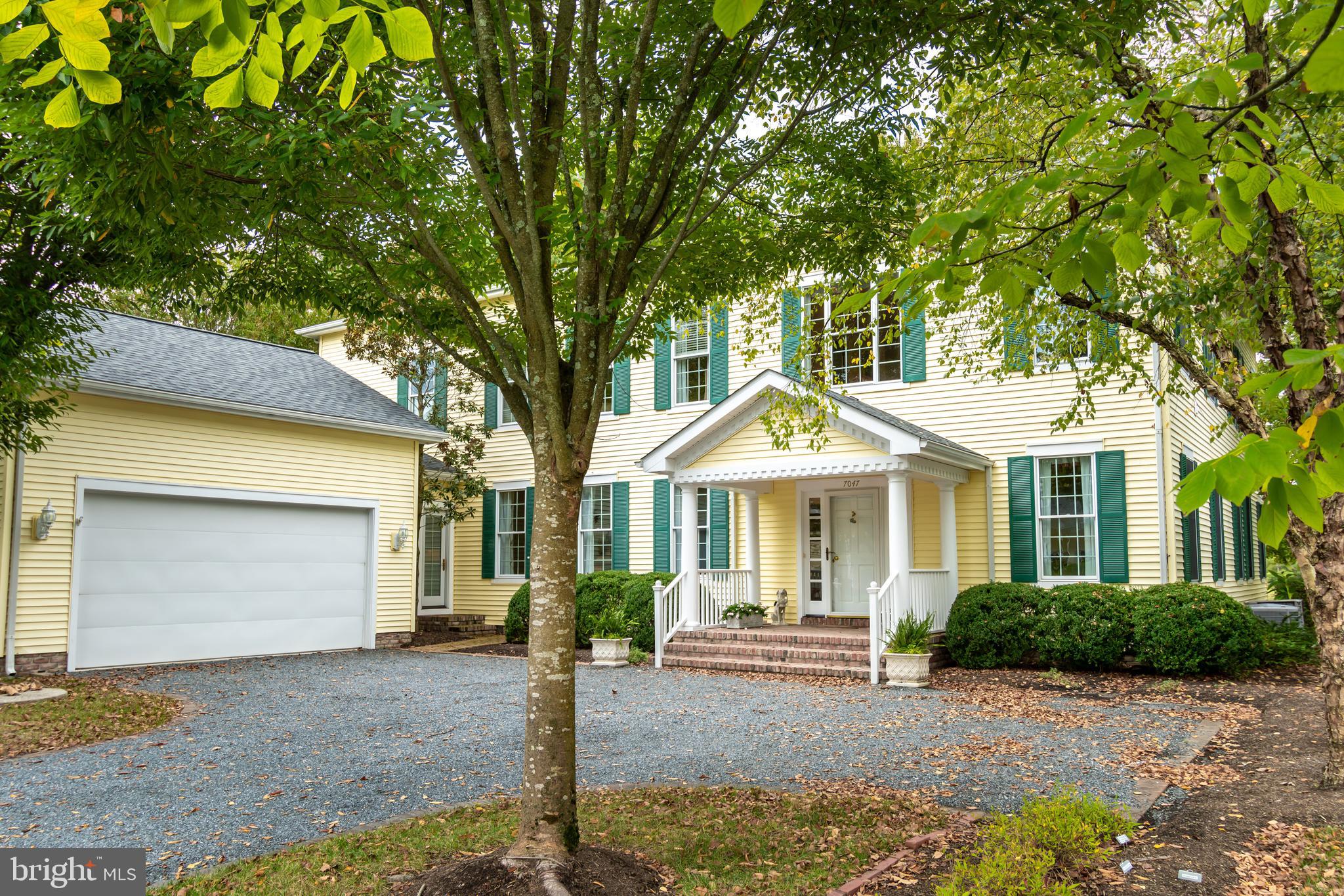 a front view of a house with plants and trees