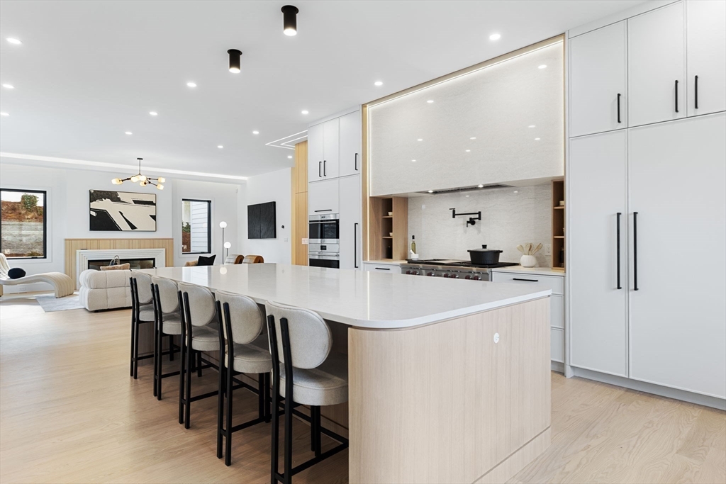 a kitchen with stainless steel appliances kitchen island a table chairs and a refrigerator