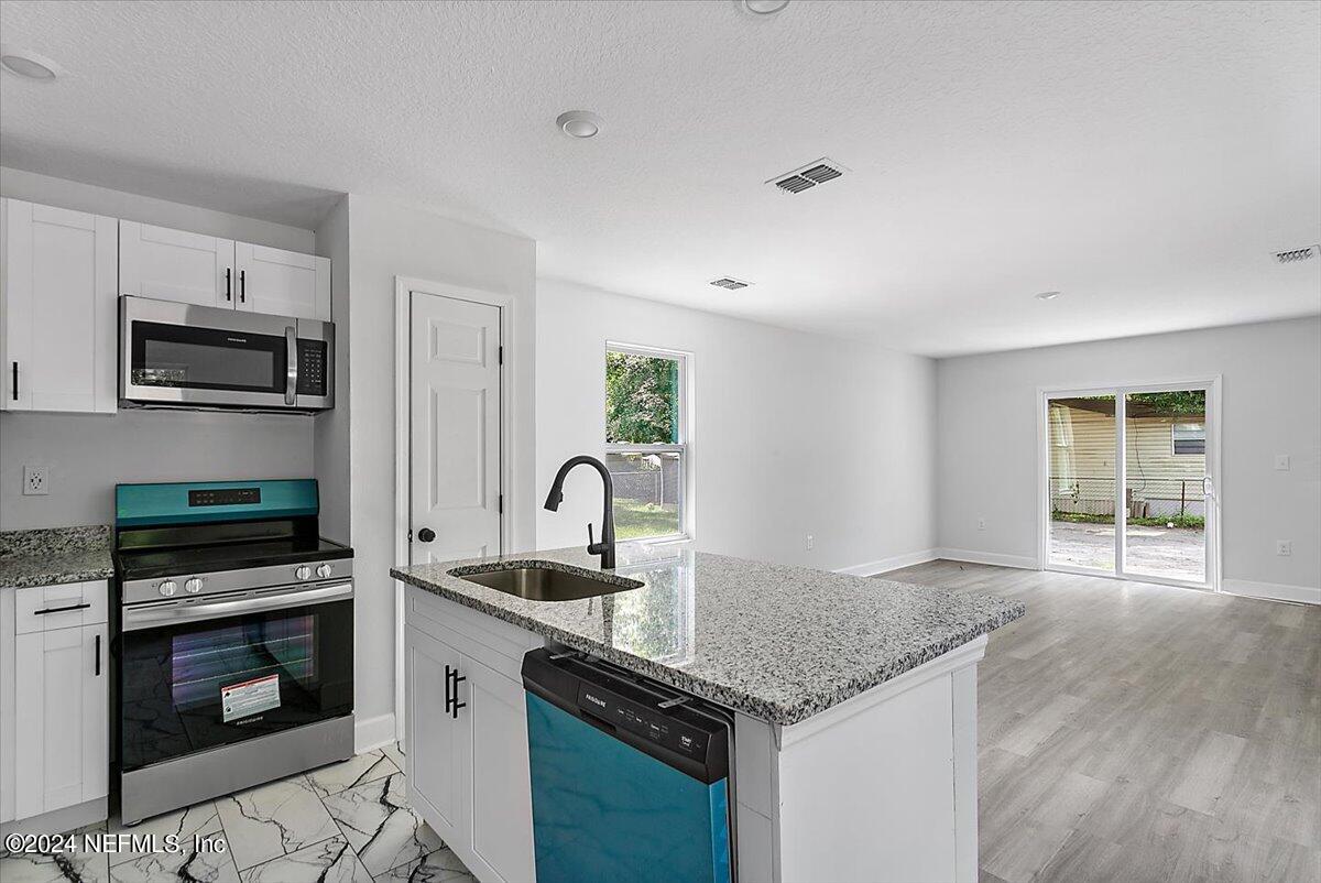 a kitchen with granite countertop a stove sink and microwave