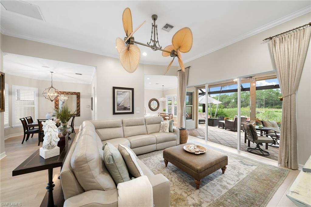 Living room with crown molding, light wood-style tile flooring, and an inviting chandelier