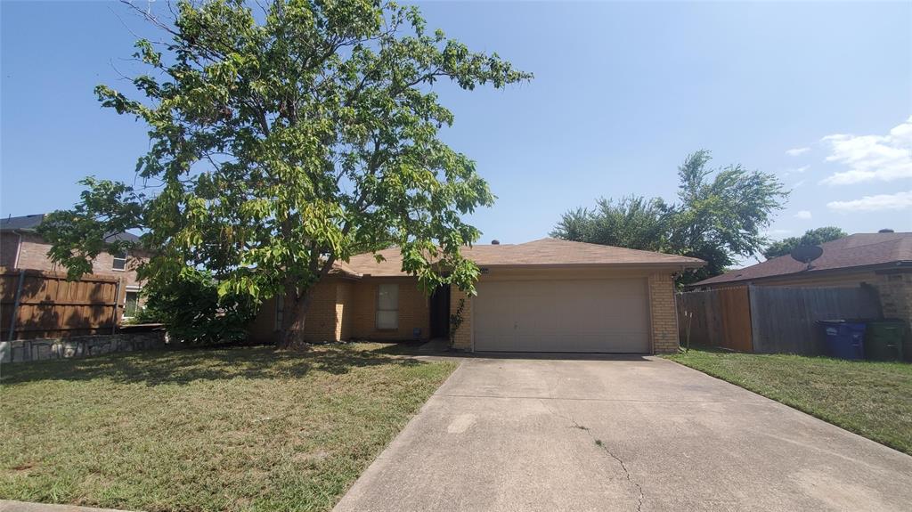 a front view of a house with a yard and tree