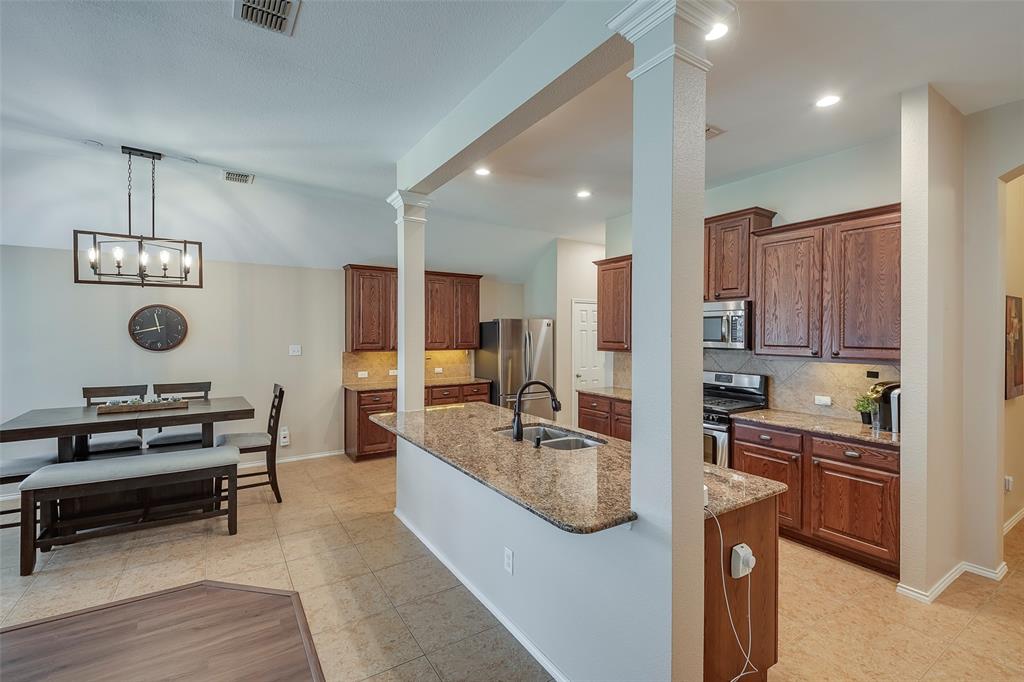 a kitchen with kitchen island granite countertop a sink and a refrigerator