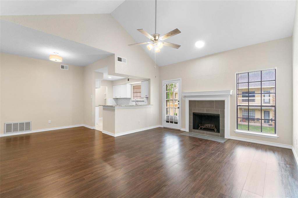 a view of an empty room with wooden floor fireplace and a window