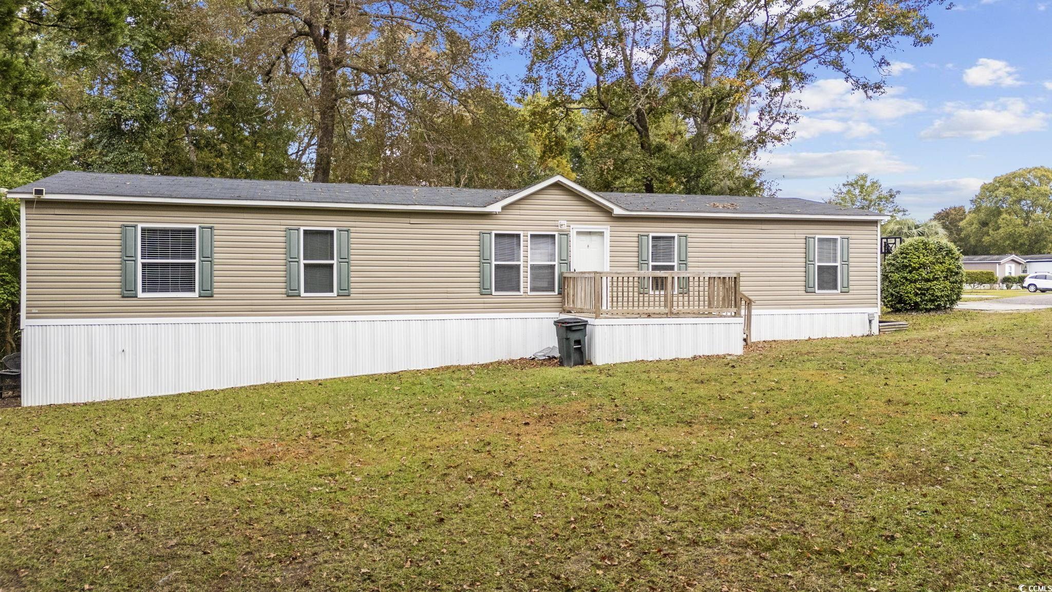 View of front of home with a deck and a front lawn