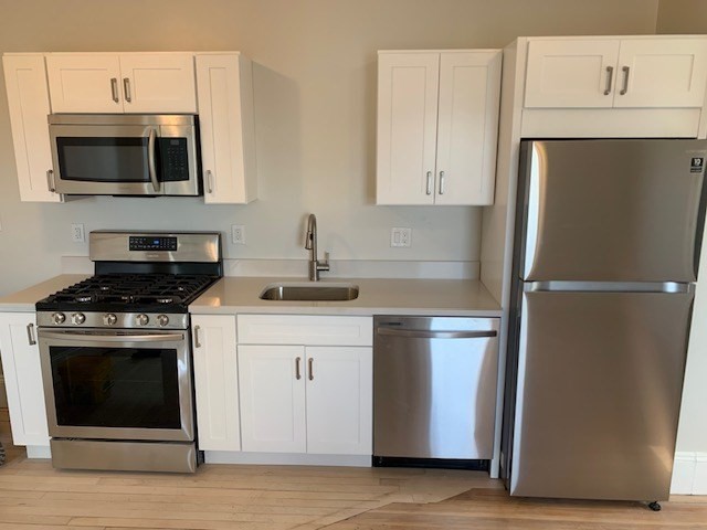 a kitchen with stainless steel appliances a stove a microwave and a sink