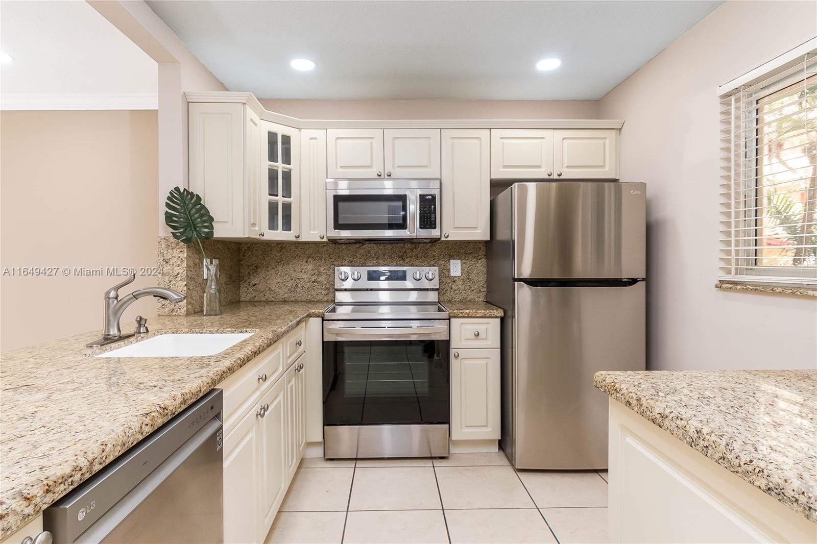 a kitchen with stainless steel appliances granite countertop a refrigerator sink stove microwave and cabinets