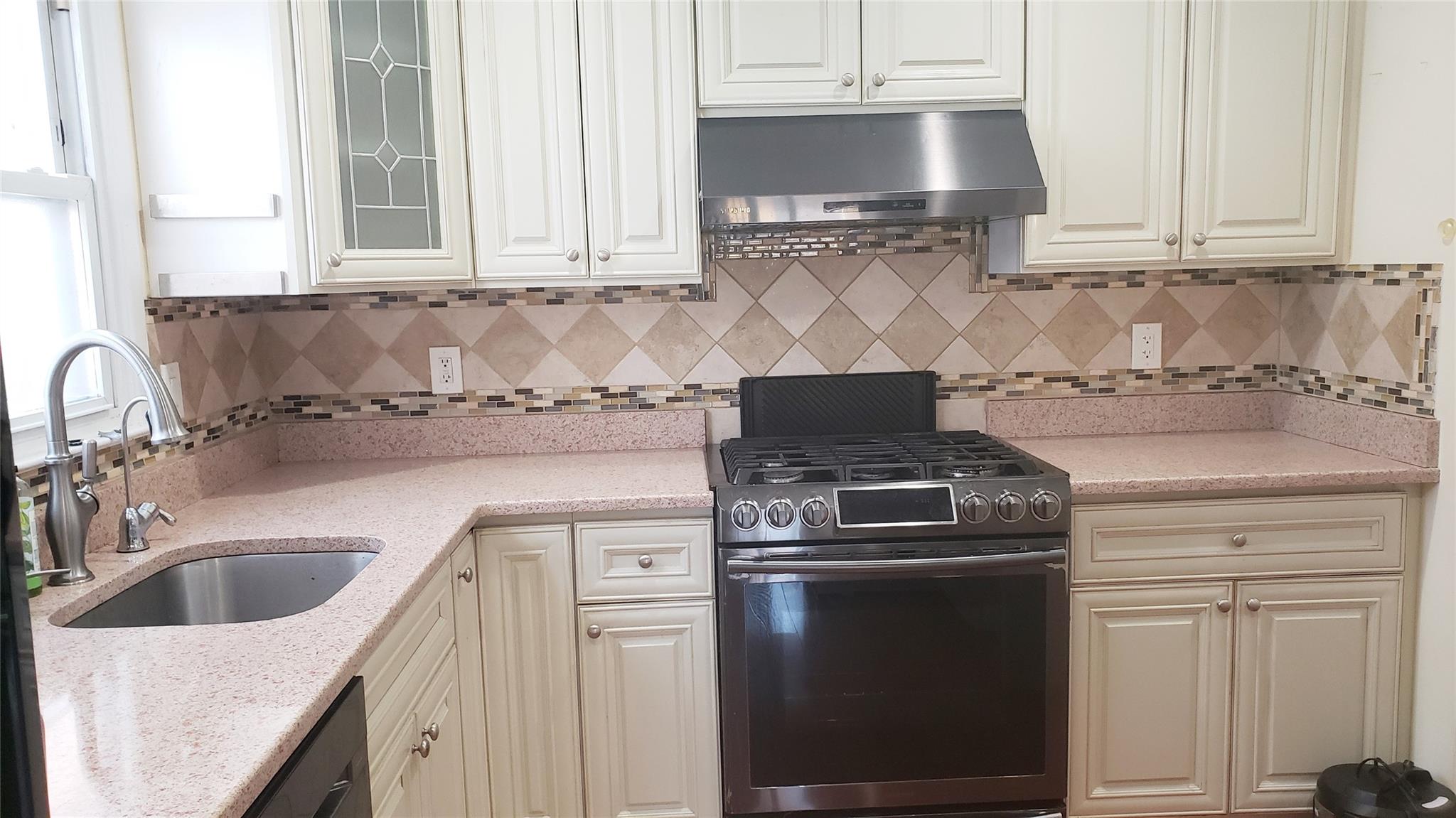 a kitchen with granite countertop white cabinets and a stove