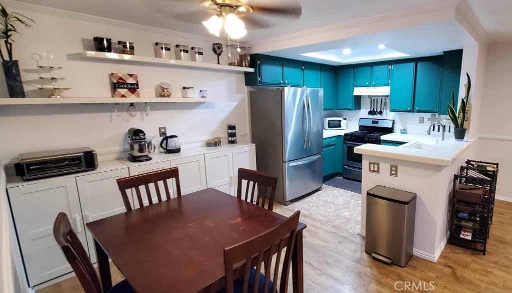 a kitchen with stainless steel appliances a dining table chairs refrigerator and cabinets