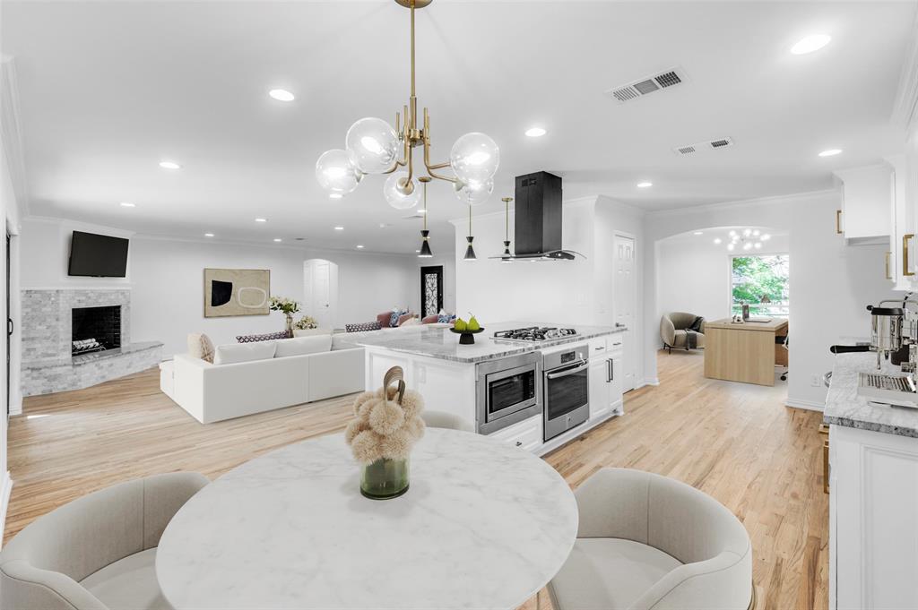 a large white kitchen with a stove a sink a center island and couches