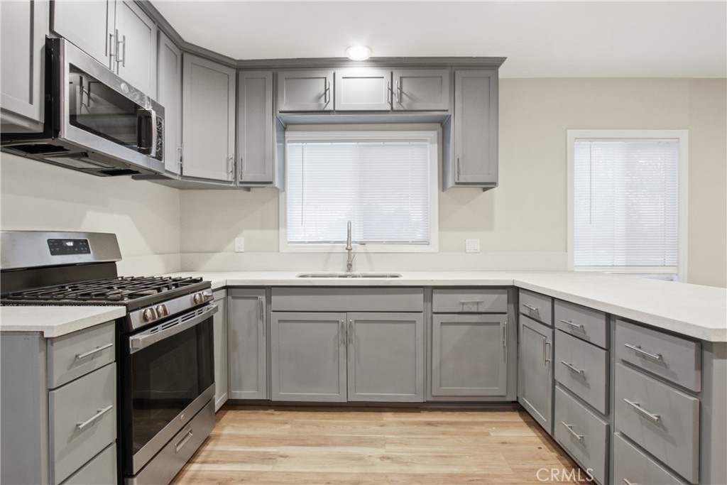 a kitchen with stainless steel appliances granite countertop a stove a sink and a microwave