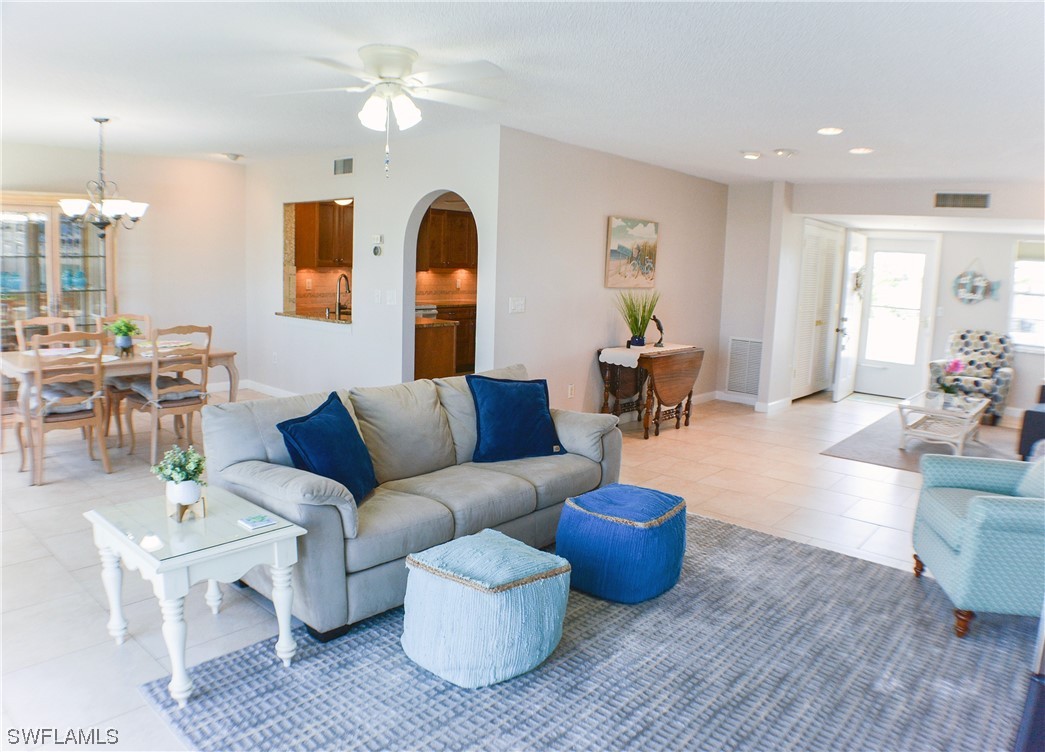 a living room with furniture a chandelier and a dining table