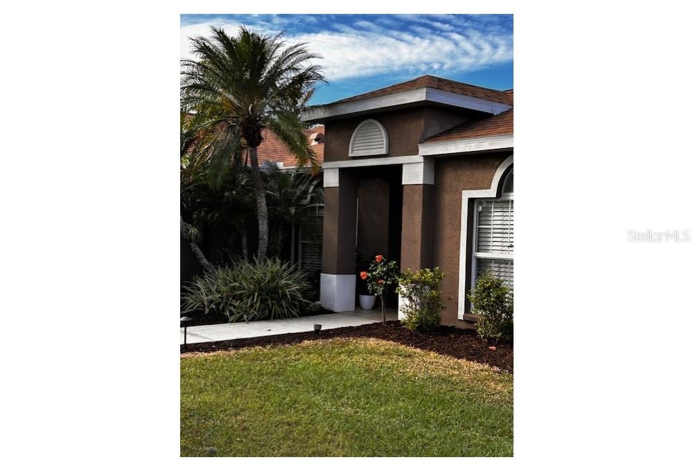 a view of a house with a small yard plants and palm trees