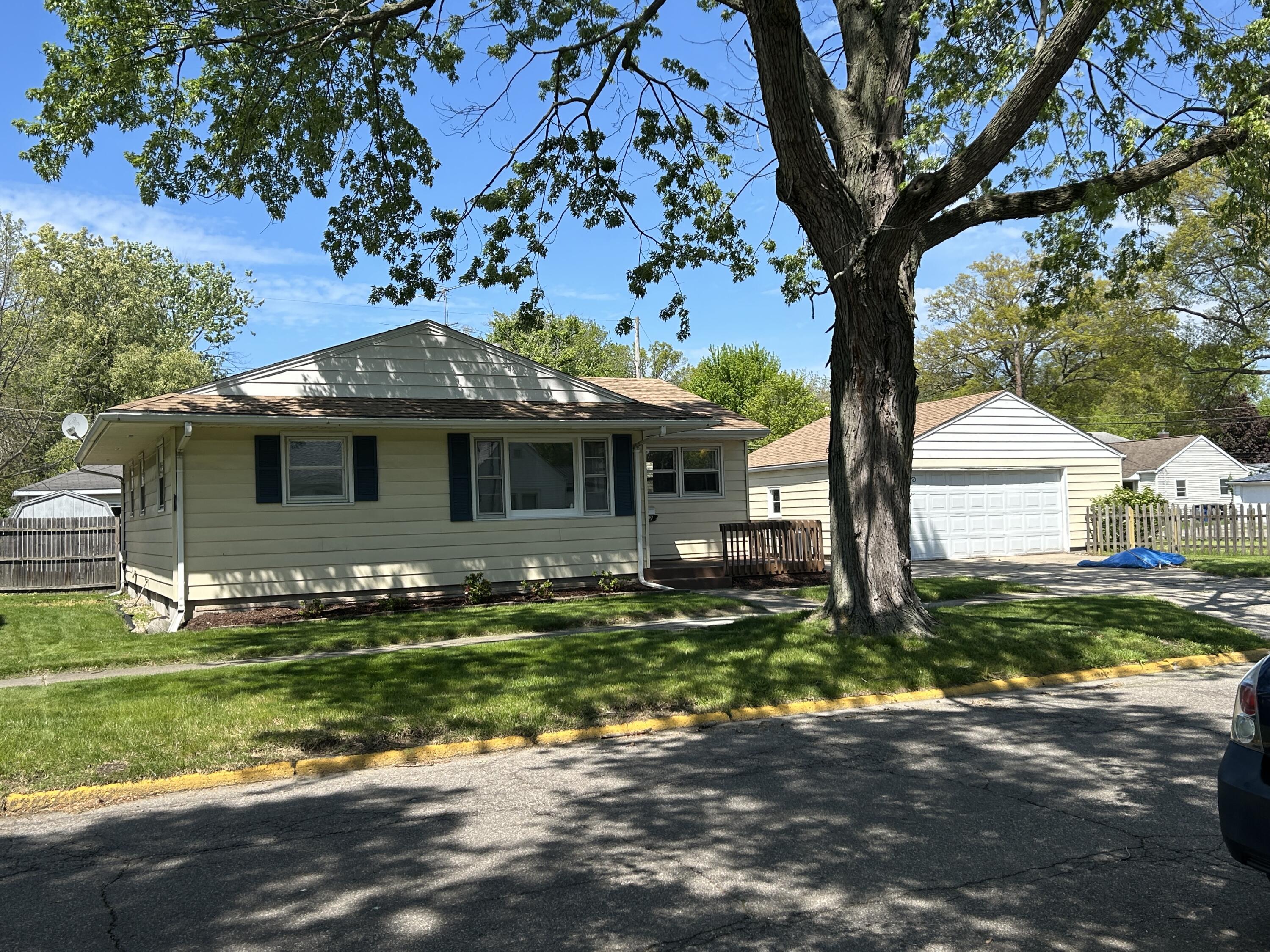 a front view of a house with a garden and tree