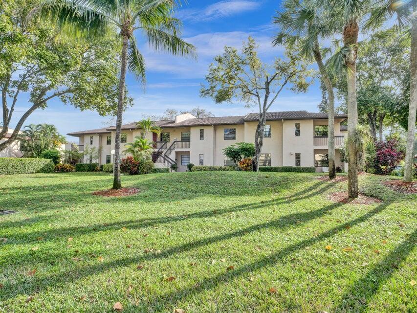 a view of a white house with a big yard and palm trees