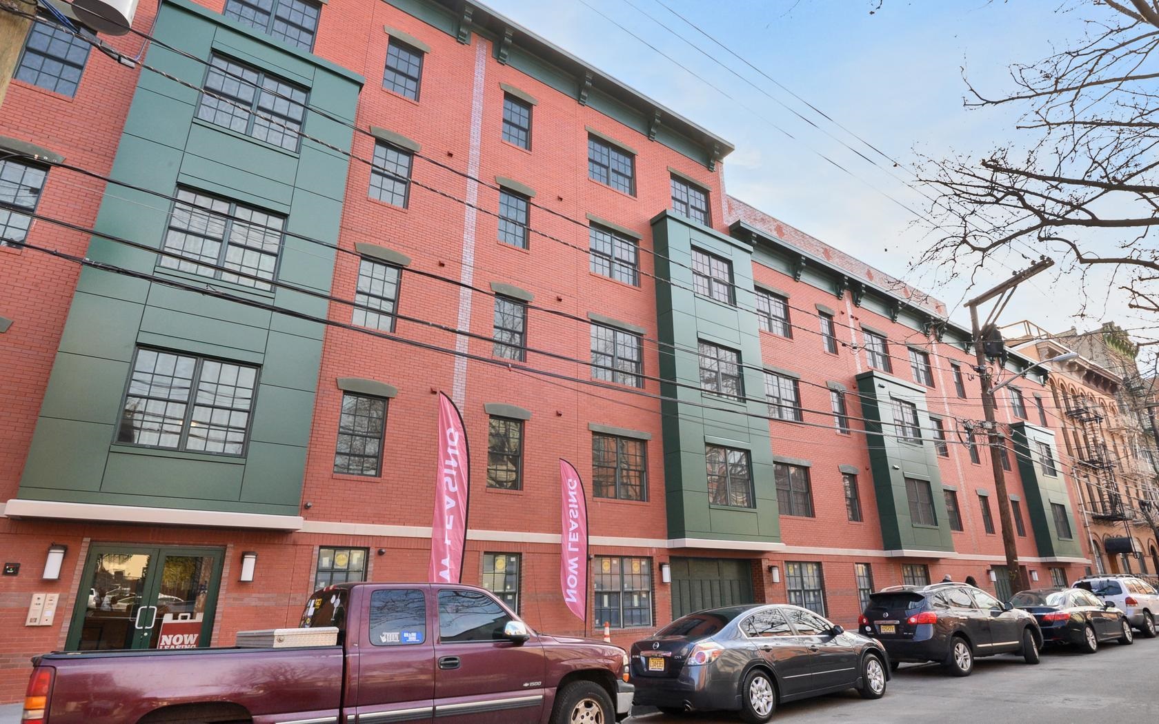 a front view of a building with lot of cars and trees