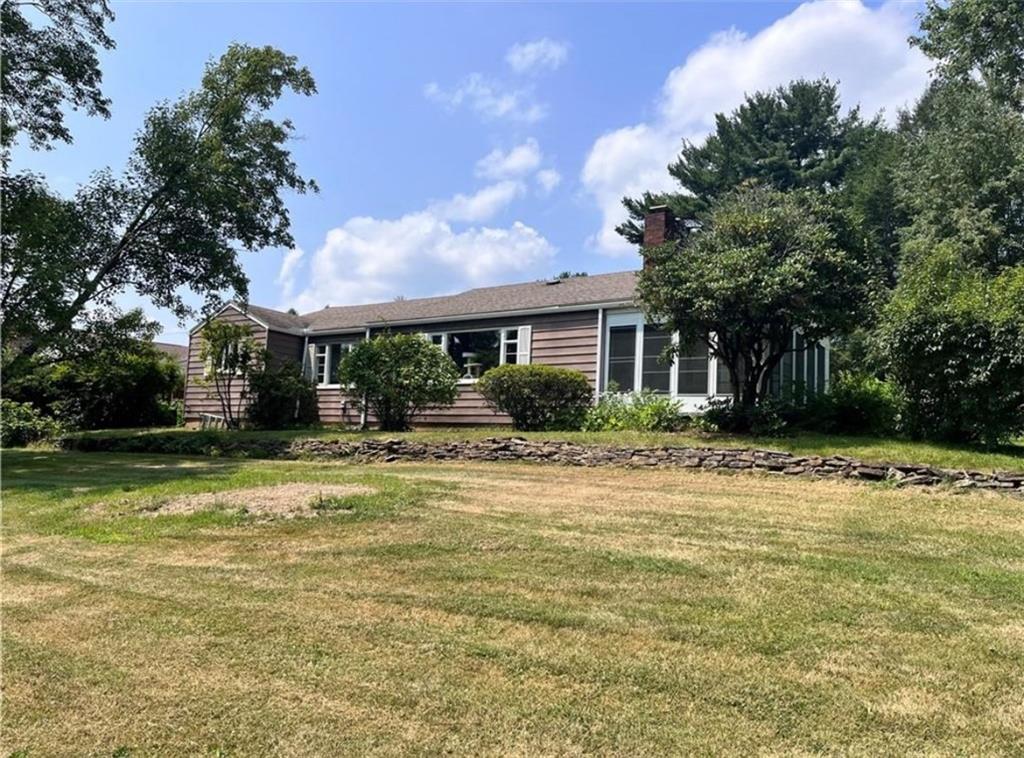 a front view of house with yard and trees in the background