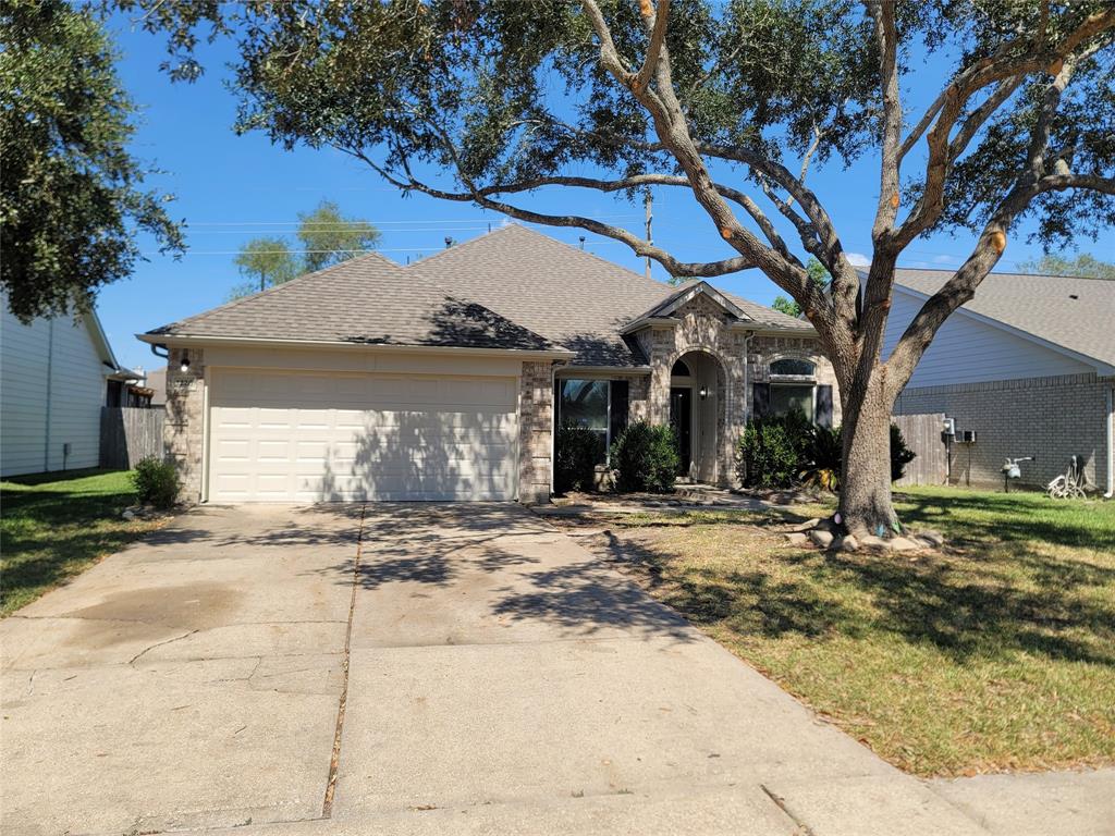 a view of a house with a yard and large tree