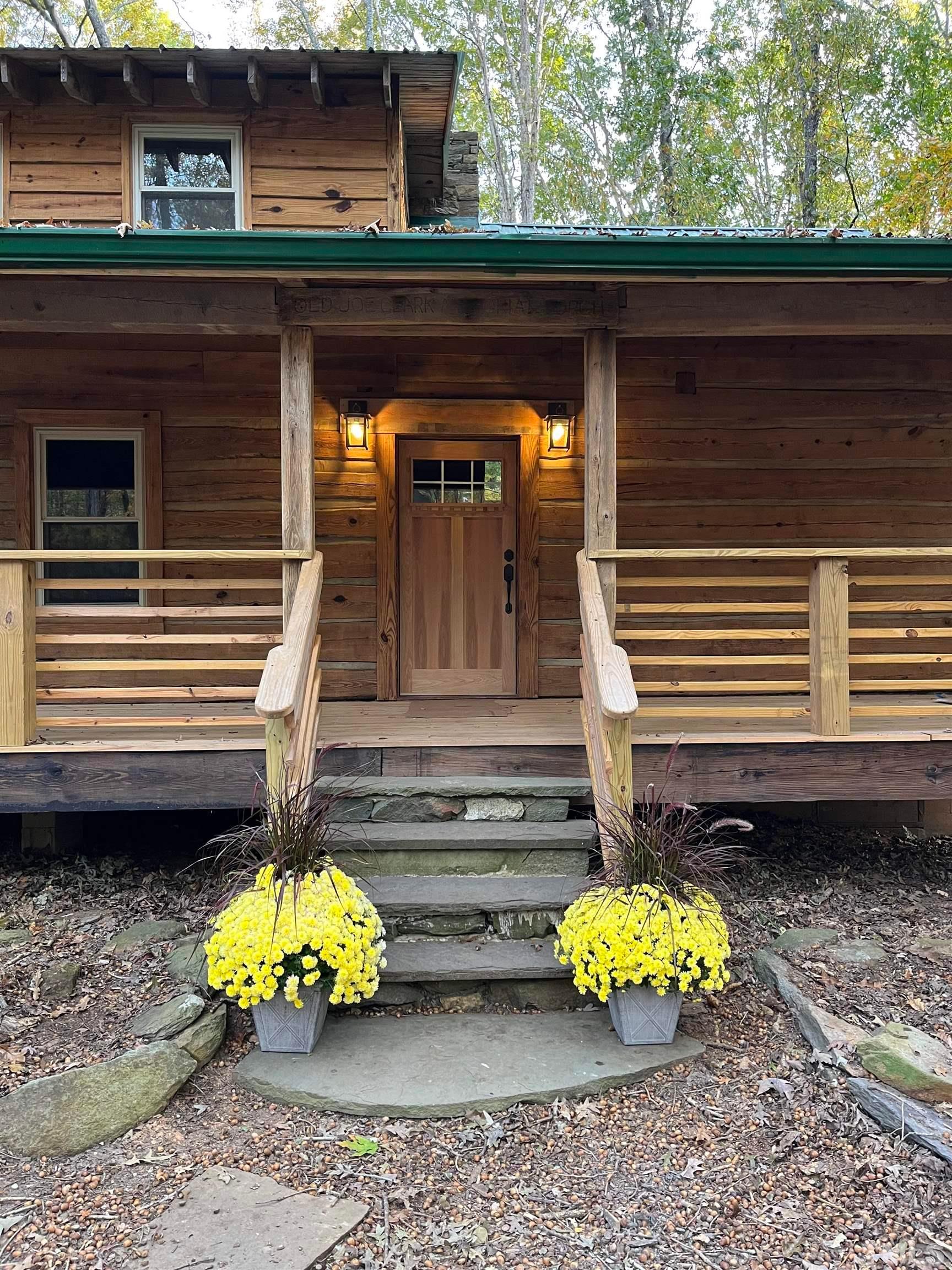 a front view of a house with a yard outdoor seating and lots of trees in the background