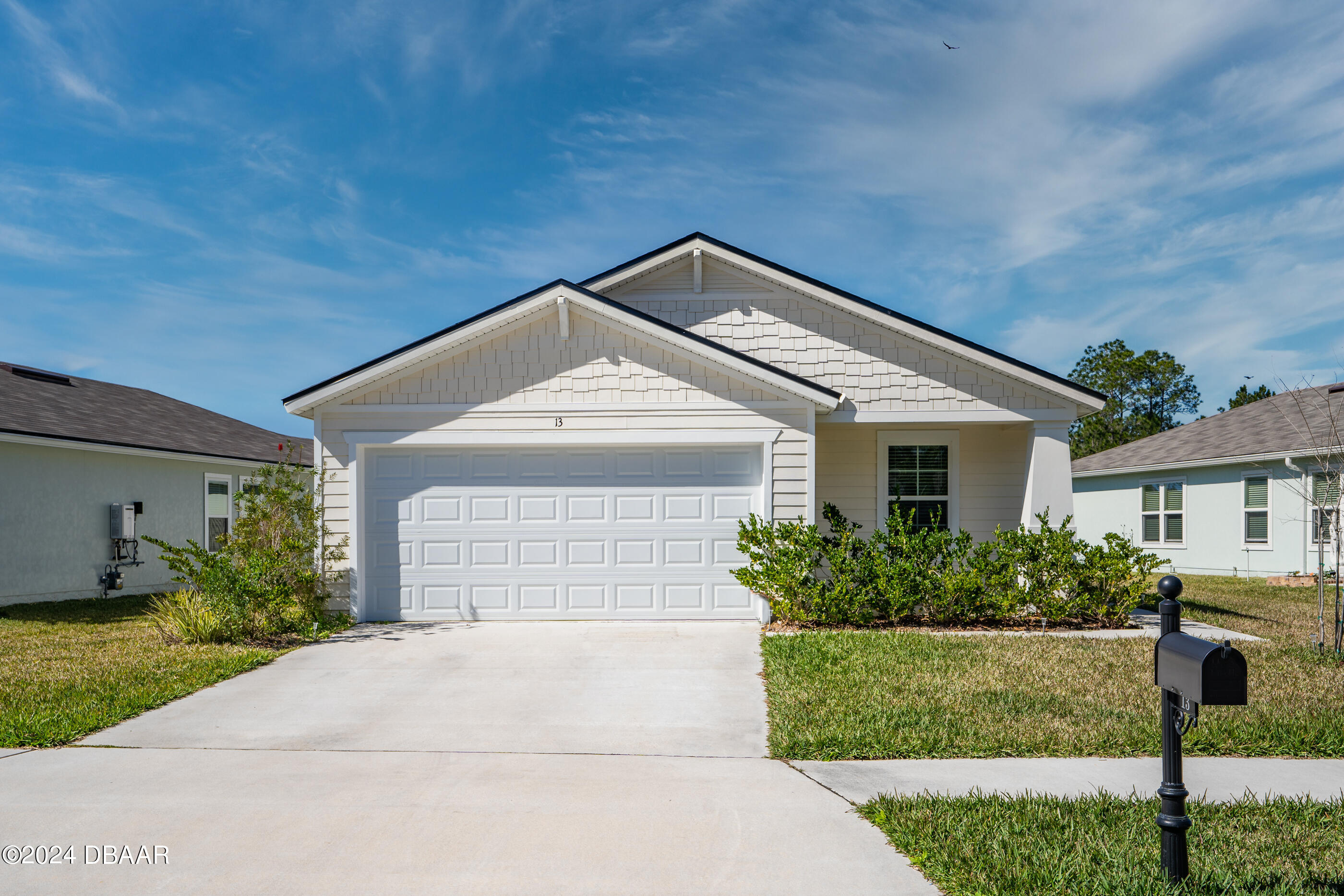 a front view of house with garage and flowers